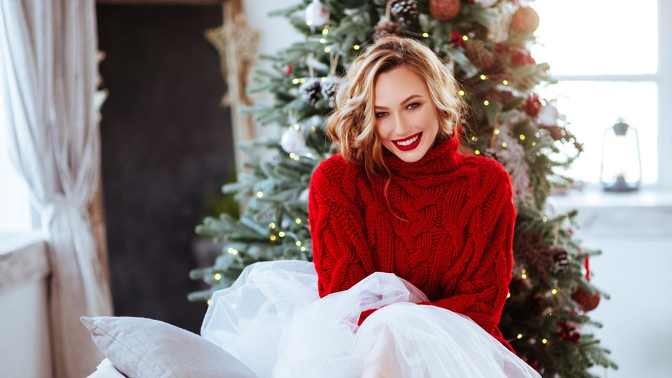 6280947c-smiling woman in red sweater over christmas tree background