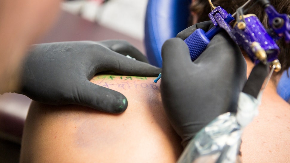 Close up of tattooist giving customer their first tattoo