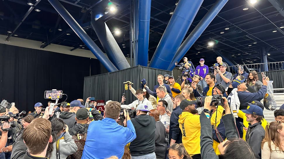 Michigan quarterback JJ McCarthy is mobbed by Michigan fans hoping to get an autograph from the star QB before the title game.