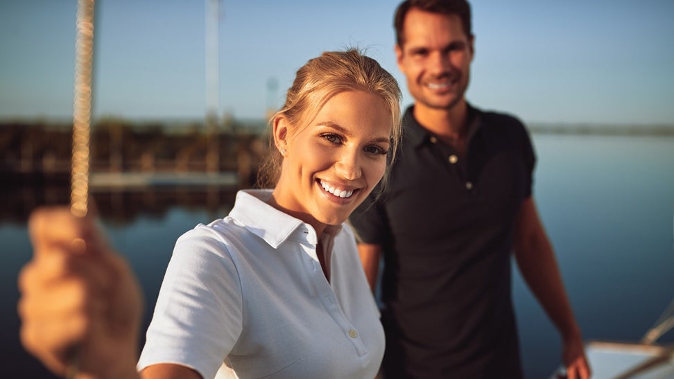 Smiling young couple standing on the deck of their yacht