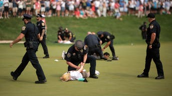 Idiot climate change protestors are ushered off the 18th green by police officers during the final round of the Travelers Championship at TPC River Highlands on June 23, 2024 in Cromwell, Connecticut. (Photo by James Gilbert/Getty Images)