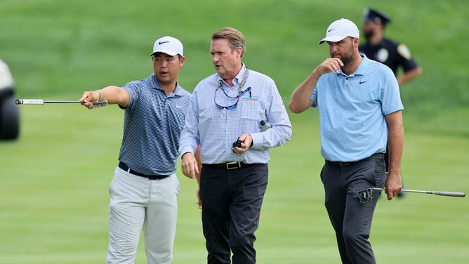 Tom Kim and Scottie Scheffler stand on the 18th green with a rules official after idiot climate protestors stormed the 18th green during the final round of the Travelers Championship at TPC River Highlands.