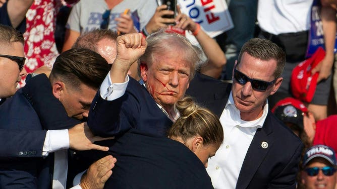 Former President Donald Trump is seen with blood on his face surrounded by secret service agents as he is taken off the stage at a campaign event in Pennsylvania. (Rebecca DROKE / AFP) (Photo by REBECCA DROKE/AFP via Getty Images)