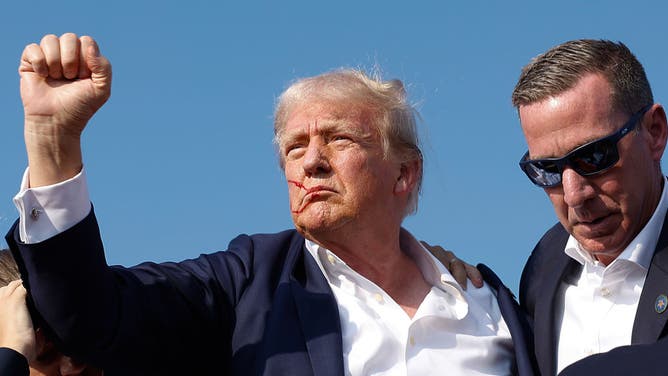 Republican presidential candidate and former U.S. President Donald Trump pumps his fist as he is rushed offstage by U.S. Secret Service agents after being hit in the ear by a bullet during a rally on July 13, 2024, in Butler, Pennsylvania.