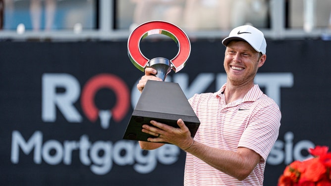 Cam Davis lifts up the trophy to celebrate winning the 2024 Rocket Mortgage Classic at Detroit Golf Club in Michigan. (Junfu Han/USA TODAY NETWORK)