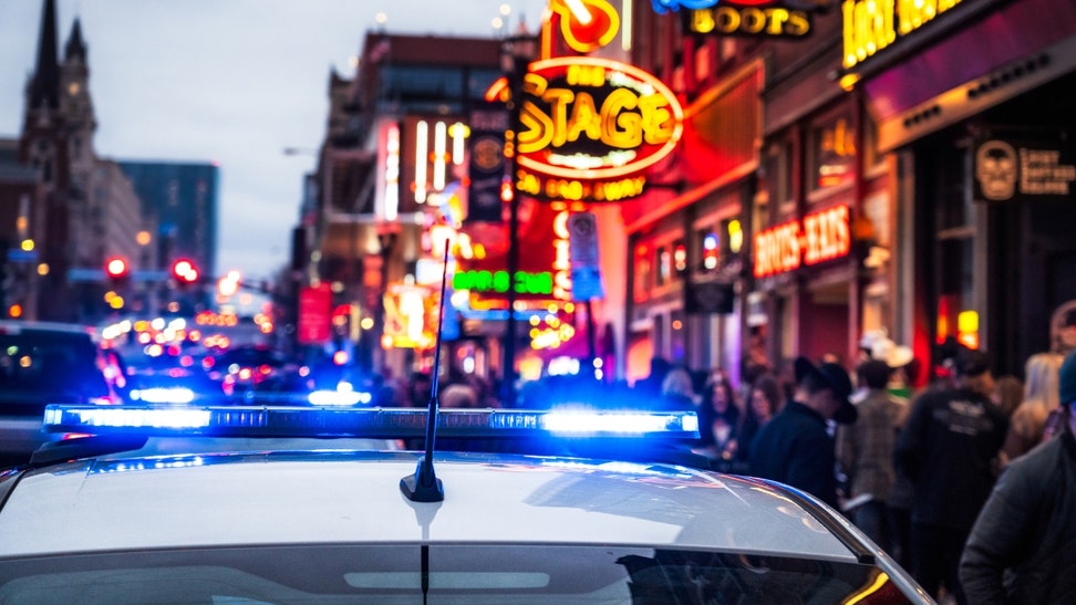 women partying broadway nashville kiss each other on police car