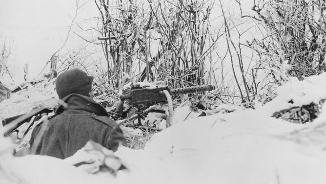 A soldier of the United States 101st Airborne Division occupies a defensive snow covered dugout foxhole position with a M1919 Browning 30 caliber medium machine gun during the Battle of the Bulge, circa January 1945, near Bastogne, Belgium. (Photo by Keystone/Hulton Archive/Getty Images)