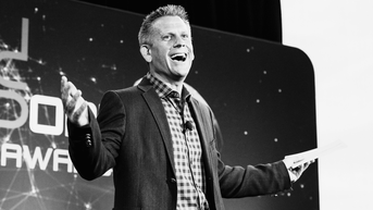 John Brenkus smiles at an event, black and white