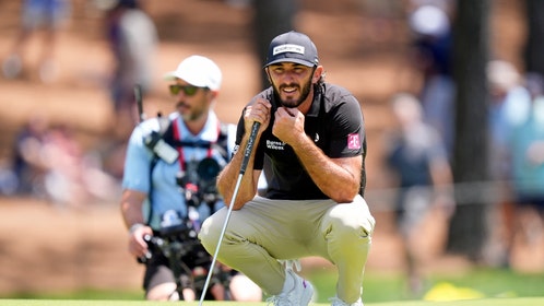 Max Homa reading a putt on a green.