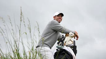 Rory McIlroy leaning on his golf bag