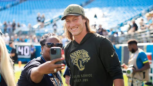 Jacksonville Jaguars quarterback Trevor Lawrence takes photos with fans before an NFL football game.