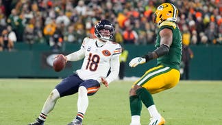 Chicago Bears QB Caleb Williams looks to pass while defended by a Green Bay Packers player.