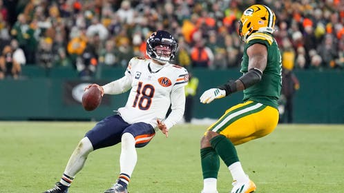 Chicago Bears QB Caleb Williams looks to pass while defended by a Green Bay Packers player.