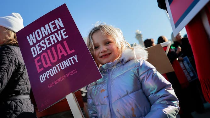 A young girl protests against transgender athletes (males) competing in women's sports outside the Supreme Court.